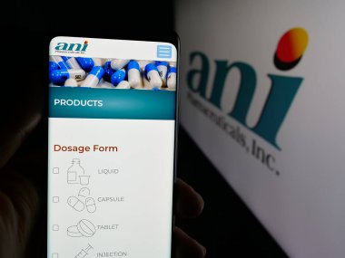 Stuttgart, Germany - 11-08-2025: Person holding cellphone with webpage of US biopharma company ANI Pharmaceuticals Inc. on screen in front of logo. Focus on center of phone display.