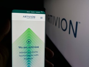 Stuttgart, Germany - 11-08-2025: Person holding cellphone with webpage of US tissue company Artivion Inc. on screen in front of logo. Focus on center of phone display.