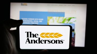 Stuttgart, Germany - 11-08-2025: Person holding cellphone with logo of US agribusiness company The Andersons Inc. on screen in front of webpage. Focus on phone display.