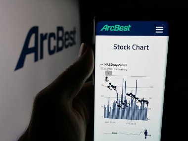 Stuttgart, Germany - 11-12-2025: Person holding smartphone with web page of US logistics company ArcBest Corporation on screen in front of logo. Focus on center of phone display.