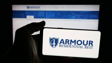 Stuttgart, Germany - 11-12-2025: Person holding mobile phone with logo of US company ARMOUR Residential REIT Inc. on screen in front of web page. Focus on phone display.