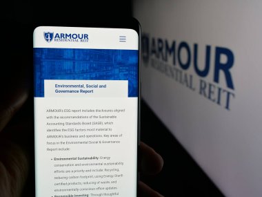 Stuttgart, Germany - 11-12-2025: Person holding smartphone with web page of US company ARMOUR Residential REIT Inc. on screen in front of logo. Focus on center of phone display.