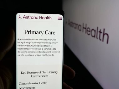 Stuttgart, Germany - 11-12-2025: Person holding cellphone with webpage of US healthcare company Astrana Health Inc. on screen in front of logo. Focus on center of phone display.