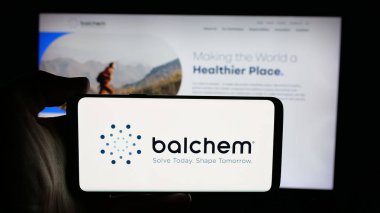 Stuttgart, Germany - 11-12-2025: Person holding cellphone with logo of nutrition and health company Balchem Corp. on screen in front of webpage. Focus on phone display.