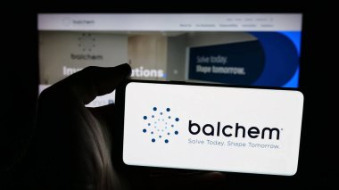 Stuttgart, Germany - 11-12-2025: Person holding mobile phone with logo of nutrition and health company Balchem Corp. on screen in front of web page. Focus on phone display.