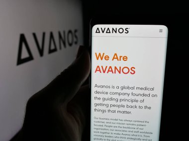 Stuttgart, Germany - 11-12-2025: Person holding smartphone with web page of US healthcare company Avanos Medical Inc. on screen in front of logo. Focus on center of phone display.