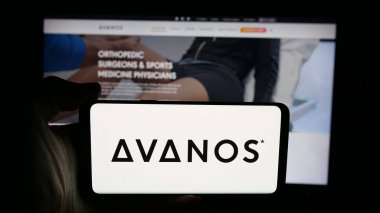 Stuttgart, Germany - 11-12-2025: Person holding cellphone with logo of US healthcare company Avanos Medical Inc. on screen in front of webpage. Focus on phone display.
