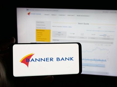 Stuttgart, Germany - 11-12-2025: Person holding smartphone with logo of financial services company Banner Corporation on screen in front of website. Focus on phone display.