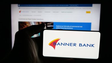 Stuttgart, Germany - 11-12-2025: Person holding mobile phone with logo of financial services company Banner Corporation on screen in front of web page. Focus on phone display.