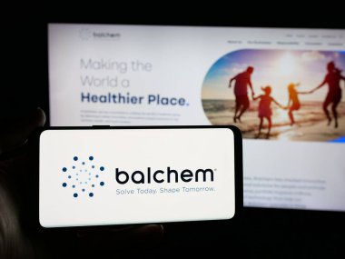 Stuttgart, Germany - 11-12-2025: Person holding smartphone with logo of nutrition and health company Balchem Corp. on screen in front of website. Focus on phone display.