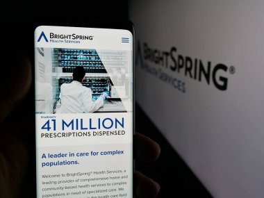 Stuttgart, Almanya - 11-14-2025: ABD 'li şirket BrightSpring Health Services Inc.' in web sayfası ile logo önünde cep telefonu tutan kişi. Telefon ekranının merkezine odaklan.