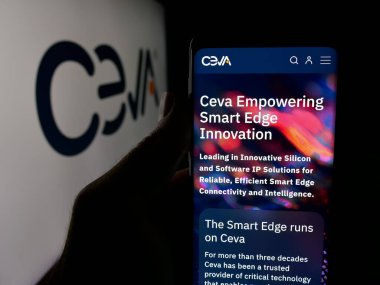 Stuttgart, Almanya - 11-14-2025: ABD 'li yarı iletken şirket Ceva Inc.' nin internet sayfası ile akıllı telefon sahibi kişi logo önünde ekranda. Telefon ekranının merkezine odaklan.