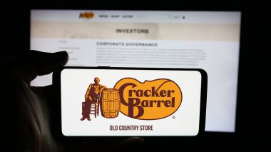 Stuttgart, Almanya - 11-14-2025: Cracker Barrel Old Country Store Inc. şirketinin logosu olan cep telefonu sahibi kişi web sayfasının önünde ekranda. Telefon ekranına odaklan.
