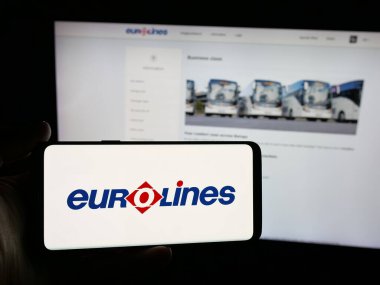 Stuttgart, Almanya - 11-18-2025: İnternet sitesinin önünde üzerinde şehir içi otobüs servisi Eurolines logosu bulunan akıllı telefon sahibi kişi. Telefon ekranına odaklan.