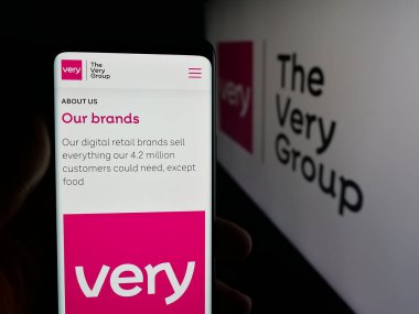 Stuttgart, Almanya - 11-19-2025: İngiliz perakende şirketi The Very Group Limited 'in web sayfası ile akıllı telefon sahibi kişi logonun önünde ekranda. Telefon ekranının merkezine odaklan.