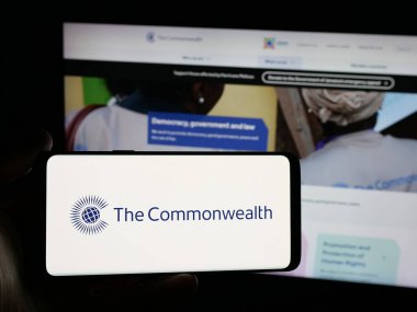 Stuttgart, Almanya - 11-19-2025: Devlet Sekreterliği kurumunun logosuna sahip akıllı telefonu web sitesi önünde ekranda tutan kişi. Telefon ekranına odaklan.