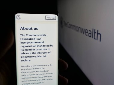 Stuttgart, Almanya - 11-19-2025: Commonwealth Secretariat sitesinin logo önündeki web sayfası ile cep telefonu tutan kişi. Telefon ekranının merkezine odaklan.