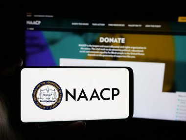 Stuttgart, Almanya - 11-19-2025: Web sitesinin önünde NAACP adlı Amerikan Zenci Derneği logosuna sahip akıllı telefon sahibi kişi. Telefon ekranına odaklan.