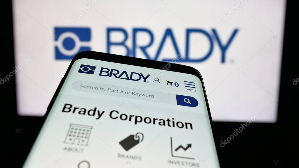 Stuttgart, Germany - 11-13-2025: Mobile phone with website of US manufacturing company Brady Corporation on screen in front of logo. Focus on top-left of phone display.