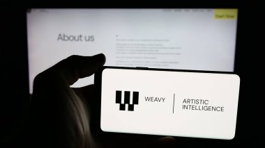Stuttgart, Almanya - 11-20-2025: Web sayfasının önünde AI şirketi Weavy Inc. 'in logosunun bulunduğu cep telefonu sahibi kişi. Telefon ekranına odaklan.