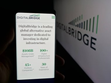 Stuttgart, Almanya - 11-20-2025: Yatırım şirketi DigitalBridge Group Inc. 'in web sayfası logonun önünde duran kişi. Telefon ekranının merkezine odaklan.