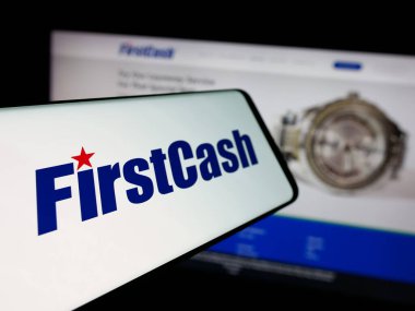 Stuttgart, Almanya - 11-20-2025: ABD 'li tefeci firması FirstCash Holding Inc.' in logosuna sahip akıllı telefon web sitesinin önünde ekranda. Telefon ekranının merkez soluna odaklan.