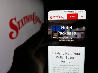 Stuttgart, Almanya - 11-20-2025: ABD 'li misafirperverlik şirketi İstasyon Kumarhaneleri LLC' nin web sayfası ile akıllı telefon sahibi kişi logonun önünde ekranda. Telefon ekranının merkezine odaklan.