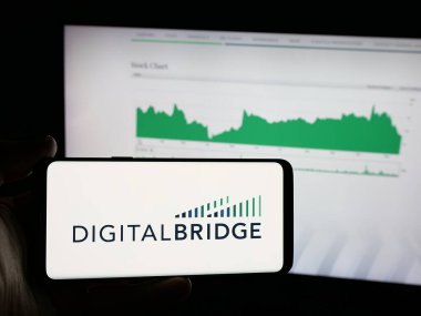 Stuttgart, Almanya - 11-20-2025: Yatırım şirketi DigitalBridge Group Inc. 'in logosunu elinde tutan kişi web sitesinin önünde ekranda. Telefon ekranına odaklan.