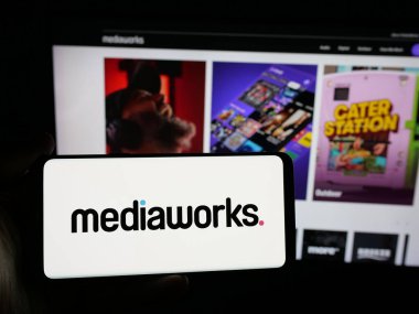 Stuttgart, Almanya - 11-21-2025: Medya şirketi MediaWorks Yeni Zelanda 'nın logosuna sahip kişi web sitesinin önünde ekranda. Telefon ekranına odaklan.