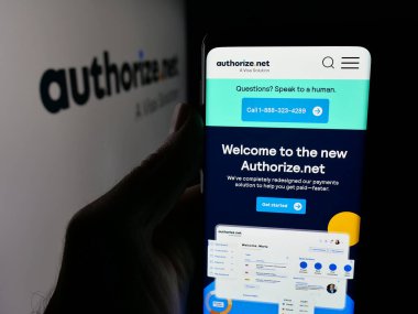 Stuttgart, Almanya - 11-21-2025: ABD ödeme kapısı şirketi Authoriz.net sitesinin web sayfası ile akıllı telefon sahibi kişi logonun önünde ekranda. Telefon ekranının merkezine odaklan.