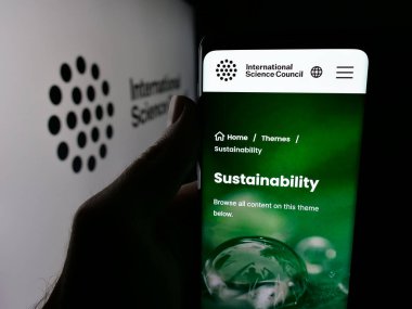 Stuttgart, Almanya - 11-23-2025: Uluslararası Bilim Konseyi 'nin (ISC) web sayfası logonun önünde cep telefonu tutan kişi. Telefon ekranının merkezine odaklan.