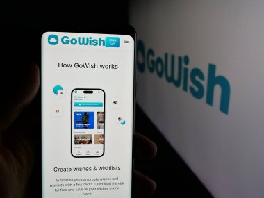 Stuttgart, Almanya - 11-23-2025: Dijital dilek platformu şirketi Gowish ApS 'in web sayfası olan akıllı telefonu logonun önünde tutan kişi. Telefon ekranının merkezine odaklan.
