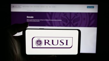 Stuttgart, Almanya - 11-24-2025: Royal United Services Institute (RUSI) logosunun bulunduğu cep telefonu web sayfası önünde ekranda. Telefon ekranına odaklan.