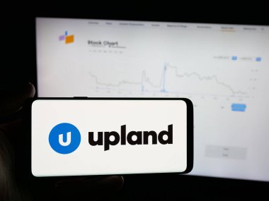 Stuttgart, Almanya - 11-26-2025: ABD 'li Upland Software Inc. şirketinin logosunu elinde tutan kişi web sitesinin önünde ekranda. Telefon ekranına odaklan.