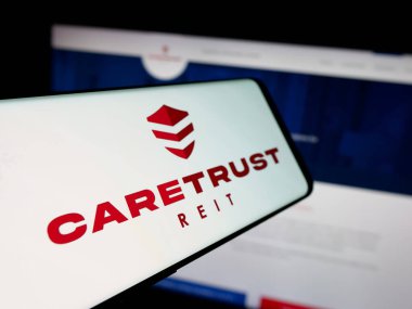 Stuttgart, Almanya - 11-27-2025: Web sitesinin önünde ekranda ABD 'li emlak şirketi CareTrust REIT Inc.' in logosuna sahip akıllı telefon. Telefon ekranının merkez soluna odaklan.
