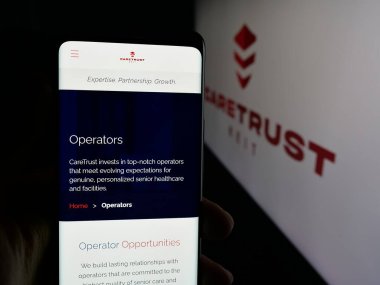 Stuttgart, Almanya - 11-27-2025: ABD 'li emlak şirketi CareTrust REIT Inc.' in web sayfası olan cep telefonu logonun önünde ekranda. Telefon ekranının merkezine odaklan.