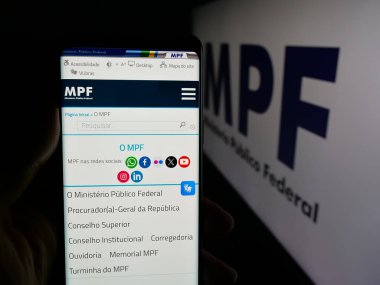 Stuttgart, Almanya - 11-28-2025: Brezilyalı Ministerio Publico Federal 'in (MPF) web sayfası logonun önünde duran kişi. Telefon ekranının merkezine odaklan.