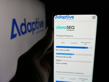 Stuttgart, Almanya - 11-28-2025: Logo önünde Adaptive Biotechnologies Corporation şirketinin web sayfası ile cep telefonu tutan kişi. Telefon ekranının merkezine odaklan.