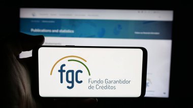 Stuttgart, Almanya - 11-28-2025: İnternet sayfasının önünde Brezilya 'nın Fundo Garantidor de Creditos (FGC) logosunun bulunduğu cep telefonu sahibi. Telefon ekranına odaklan.