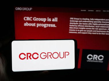 Stuttgart, Almanya - 11-28-2025: ABD 'li şirket CRC Sigorta Hizmetleri' nin logosuna sahip akıllı telefon sahibi kişi web sitesi önünde ekranda. Telefon ekranına odaklan.