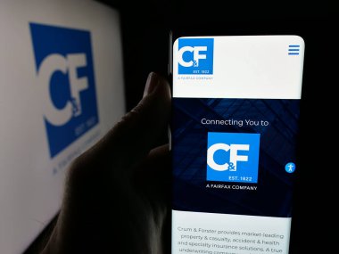 Stuttgart, Almanya - 11-28-2025: ABD 'li sigorta şirketi Crum ve Forster' ın (CF) internet sayfası logo önünde cep telefonu tutan kişi. Telefon ekranının merkezine odaklan.