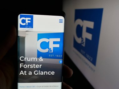 Stuttgart, Almanya - 11-28-2025: ABD 'li sigorta şirketi Crum ve Forster' ın (CF) web sitesi ile akıllı telefon sahibi kişi logonun önünde ekranda. Telefon ekranının merkezine odaklan.
