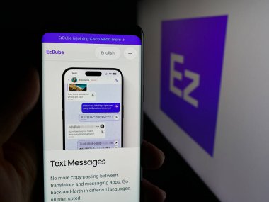 Stuttgart, Almanya - 11-30-2025: Telefon çeviri şirketi EzDubs Inc. 'in web sayfası ile akıllı telefonu olan kişi logonun önünde ekranda. Telefon ekranının merkezine odaklan.