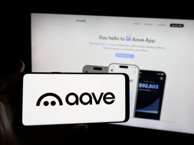 Stuttgart, Almanya - 11-30-2025: İngiliz yazılım şirketi Aave Labs 'in logosunu elinde tutan kişi web sitesinin önünde ekranda. Telefon ekranına odaklan.