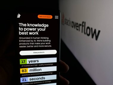 Stuttgart, Almanya - 11-30-2025: Logonun önünde Stack Exchange Inc. 'nin web sayfası olan akıllı telefon sahibi kişi. Telefon ekranının merkezine odaklan.
