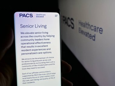 Stuttgart, Almanya - 11-30-2025: ABD 'li sağlık şirketi PACS Group Inc.' in web sayfası olan cep telefonu logonun önünde ekranda. Telefon ekranının merkezine odaklan.