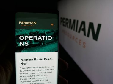 Stuttgart, Almanya - 12-02-2025: ABD 'li petrol şirketi Permian Resources Corporation' ın web sayfası ile logo önünde cep telefonu tutan kişi. Telefon ekranının merkezine odaklan.