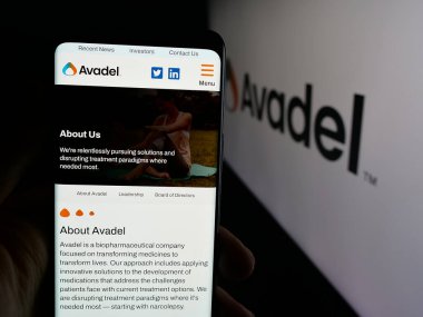 Stuttgart, Almanya - 12-02-2025: İrlandalı Avadel Pharmaceuticals plc şirketinin web sayfası logonun önünde duran kişi. Telefon ekranının merkezine odaklan.