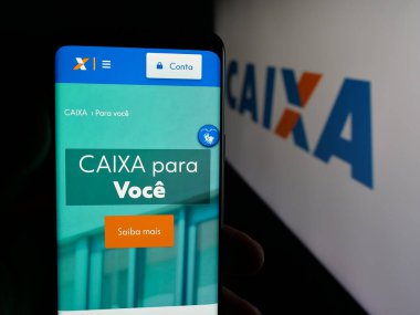 Stuttgart, Almanya - 12-02-2025: Brezilyalı Caixa Economica Federal (CEF) web sitesi logonun önünde cep telefonu tutan kişi. Telefon ekranının merkezine odaklan.