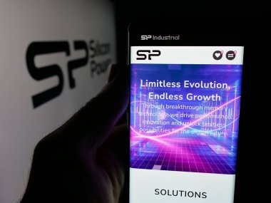 Stuttgart, Almanya - 12-02-2025: Logonun önündeki ekranda Silikon Power Communications Inc. 'in web sayfası ile akıllı telefon tutan kişi. Telefon ekranının merkezine odaklan.